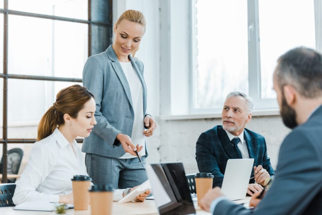 WiFi or Wireless Internet Technical Support 3 cheerful business coach standing near coworkers and gesturing near digital tablet